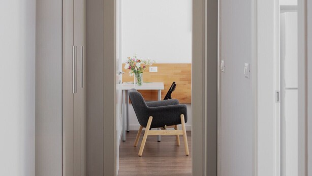 Ein Korridor mit Holzboden, einem Schreibtisch mit Stuhl und Blick auf einen Balkon.