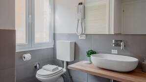 Ein modernes Badezimmer mit Toilette, Waschbecken und Fenster.