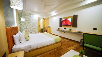 A hotel room with a bed, a desk, a chair, a television, and a ceiling fan.