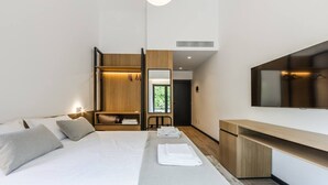 A modern hotel room with a bed, bedside table, TV, and a walk-in closet.