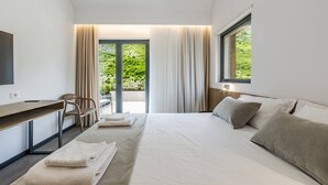 A modern hotel room with a bed, a desk, a chair, and a large window with curtains.