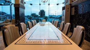 A conference room with a marble table and leather chairs, large windows, and a view of the city. - Rabigh Tower Hotel (Rabigh)