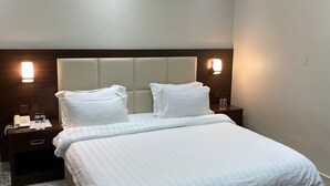A hotel room with a large bed, two bedside tables, a nightstand, and a decorative ceiling.