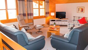 Una sala de estar acogedora con un sofá, un sillón y un televisor.