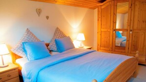 Un dormitorio con una cama de madera, dos mesitas de noche con lámparas, un armario y decoraciones de corazón en la pared.