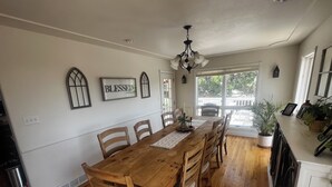 A dining area with a wooden table and chairs, a chandelier, and a view through a glass door. - Spacious 5-bedroom house in Cheyenne with AC, fitness room, outdoor space (Cheyenne)