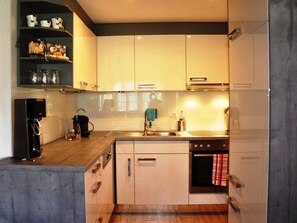 Eine kleine Küche mit weißen Schränken, einem Edelstahl-Spülbecken und einem eingebauten Backofen.