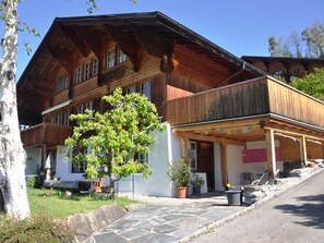 Eine Holzchalet mit Balkon, Blumentöpfen und einem Steinweg.