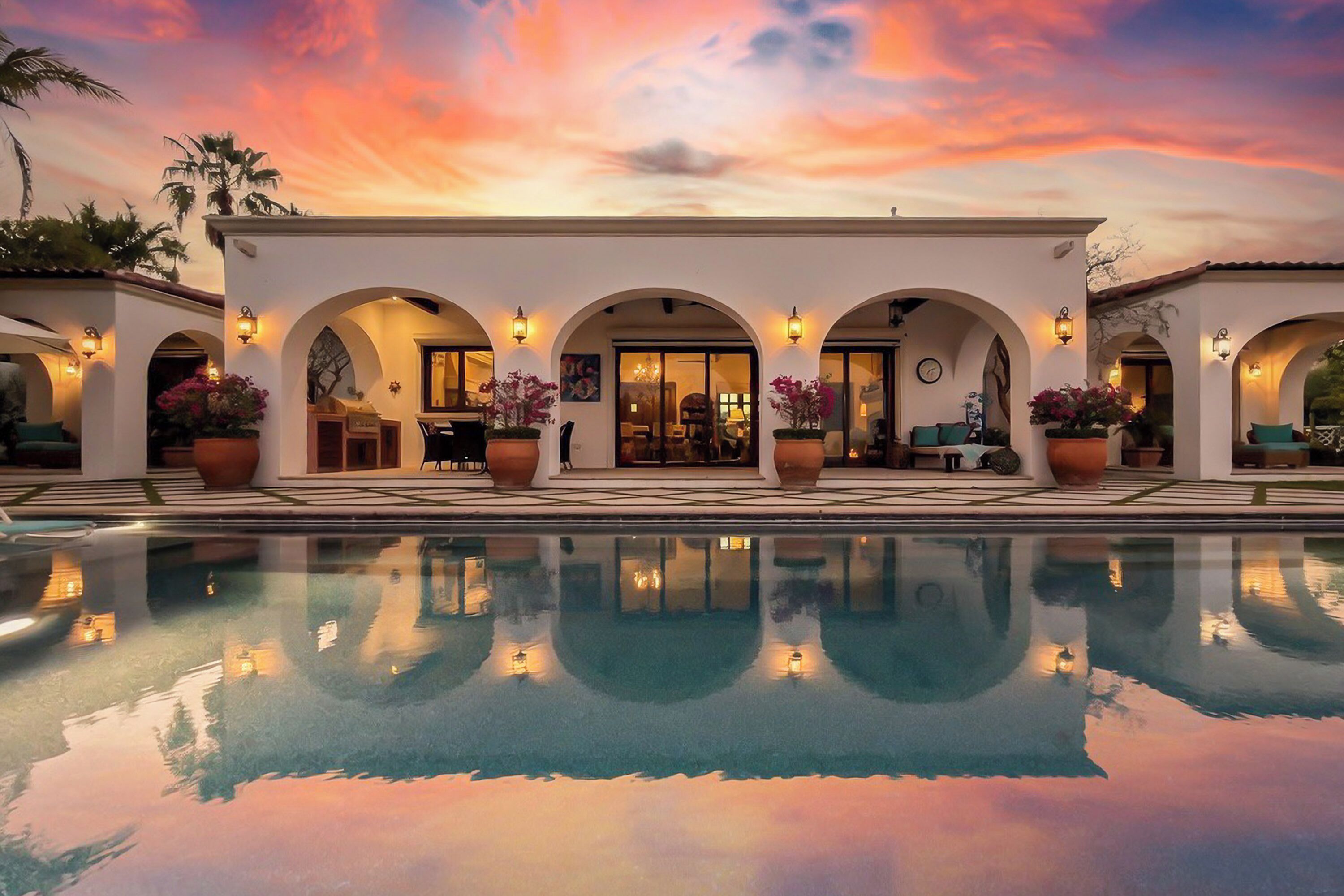A poolside area with a sunset view, arched walkways, and potted plants.