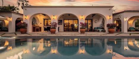 A poolside area with a sunset view, arched walkways, and potted plants.