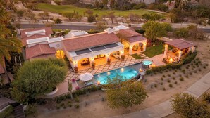 Una casa grande con piscina, varios patios y un jardín bien cuidado.