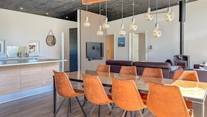 A modern kitchen with a central island, a dining area with orange chairs, and a living area with a sofa and fireplace. - Pet friendly home in Fur with WiFi (Fur)