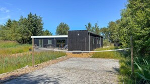 Ein modernes Gebäude mit einer Terrasse, umgeben von dichter Vegetation.