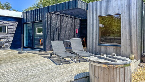 Ein moderner Außenbereich mit zwei Lounge-Stühlen und einer Holzterrasse.