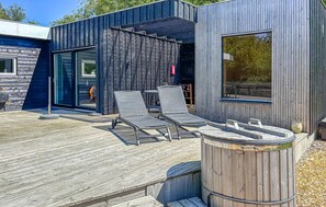 A modern outdoor seating area with two lounge chairs and a wooden deck.
