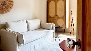 Ein Zimmer mit einem weißen Sofa, einer Holzkommode, einer Giraffenskulptur und einem roten Tisch.