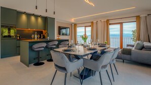 A modern kitchen with a dining area, a sofa, and a view of the sea. - Amazing home in Zukova (Zukova)