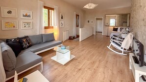 Una sala de estar moderna con un sofá gris, una mesa de centro de vidrio y una mecedora blanca.