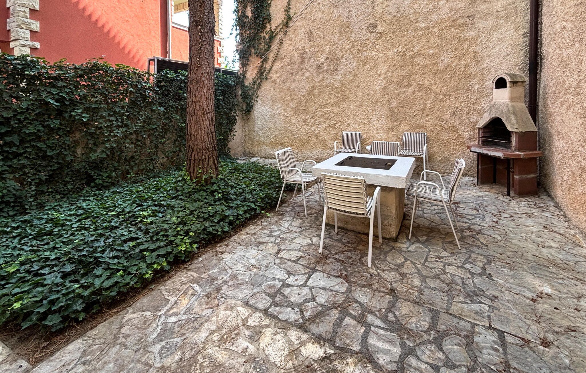 Una terrazza esterna con pavimento in pietra, un tavolo con sedie e un forno a mattoni.