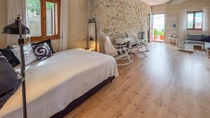Un dormitorio con cama, escritorio, mecedora y televisor.
