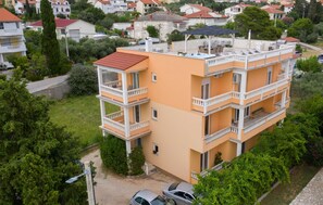 A multi-story residential building with balconies, a rooftop terrace, and a surrounding green area. - 1 bedroom lovely apartment in Rab Barbat (Rab Barbat)
