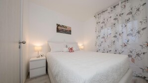 Una camera da letto con un letto, comodini, un quadro e tende floreali.