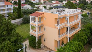 Un edificio residenziale a più piani con balconi, immerso nel verde e circondato da altre case.