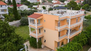 A multi-story building with balconies, a rooftop terrace, and a surrounding green landscape. - Amazing apartment in Rab Barbat with WiFi (Rab Barbat)