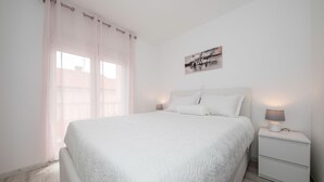 A bedroom with a bed, bedside lamps, a nightstand, a window with sheer curtains, and a wall-mounted picture. - Amazing apartment in Rab Barbat with WiFi (Rab Barbat)