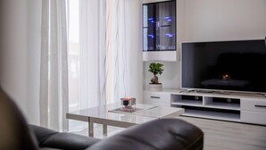 Ett modernt vardagsrum med en soffa, ett soffbord, en tv och en krukväxt.