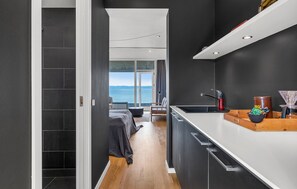 A modern kitchen with a view to the sea, a dining area with a view, and a bedroom with a large window. - 1 bedroom beautiful apartment in Ebeltoft (Ebeltoft)