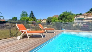Une piscine avec une terrasse en bois et des chaises longues.