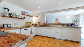 Une cuisine moderne avec un plan de travail en bois, des armoires blanches et une grande fenêtre.