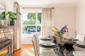 Ein Essbereich mit einem Tisch für vier Personen, einem Kamin und Blick auf die Straße.