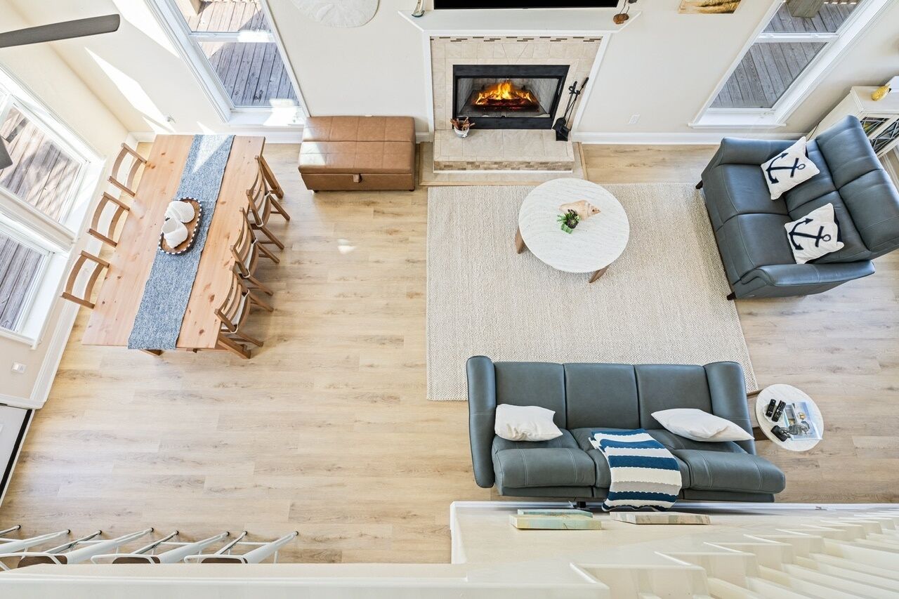 A modern living room with a fireplace, a dining area with wooden chairs, and a grey sofa with decorative pillows.