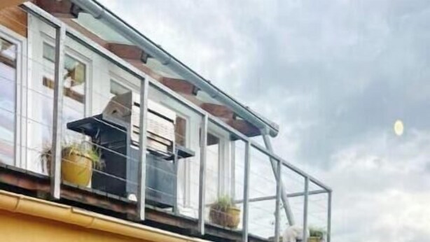Un bâtiment jaune doté d’un balcon, de grandes fenêtres et d’une terrasse en bois.