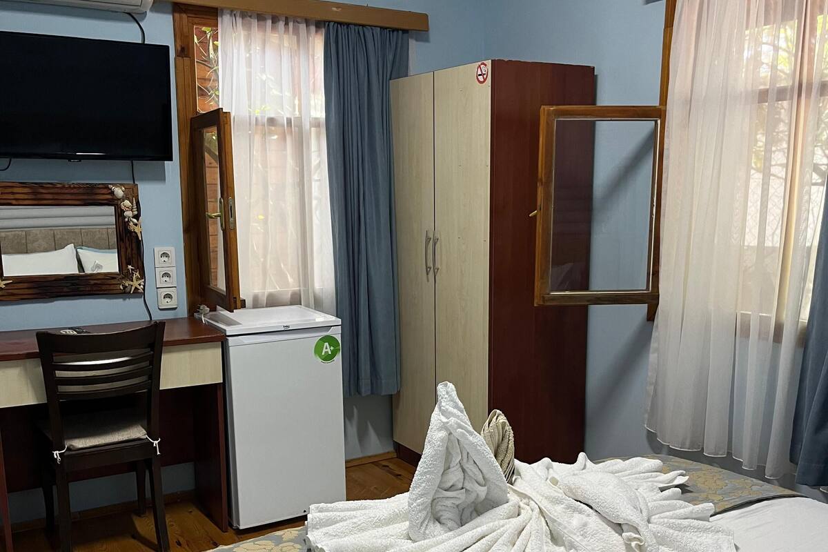 Ein Hotelzimmer mit einem Bett, einem Schreibtisch mit Stuhl, einem Fernseher und einem Kleiderschrank.