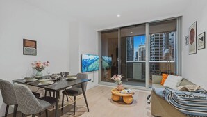 A modern living room with a dining area, large windows, and a sofa with cushions. - Puddings Designer 2B2B WSP | CBD Southern Cross (Melbourne)