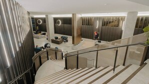 A modern interior with a curved staircase, a seating area, and a wall with vertical lines. - Puddings Designer 2B2B WSP | CBD Southern Cross (Melbourne)
