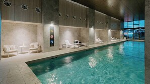 An indoor swimming pool with lounge chairs and a sign with symbols. - Puddings Designer 2B2B WSP | CBD Southern Cross (Melbourne)