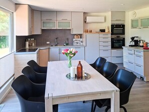 Una cocina moderna con una mesa de comedor, sillas y un florero.