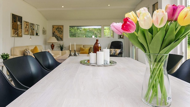 Ein Essbereich mit Tisch für vier Personen, einer Tulpenvase und Blick auf das Wohnzimmer.