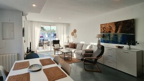 Ein modernes Wohnzimmer mit Essbereich, einer Couch, einem Couchtisch und einem Bild an der Wand.