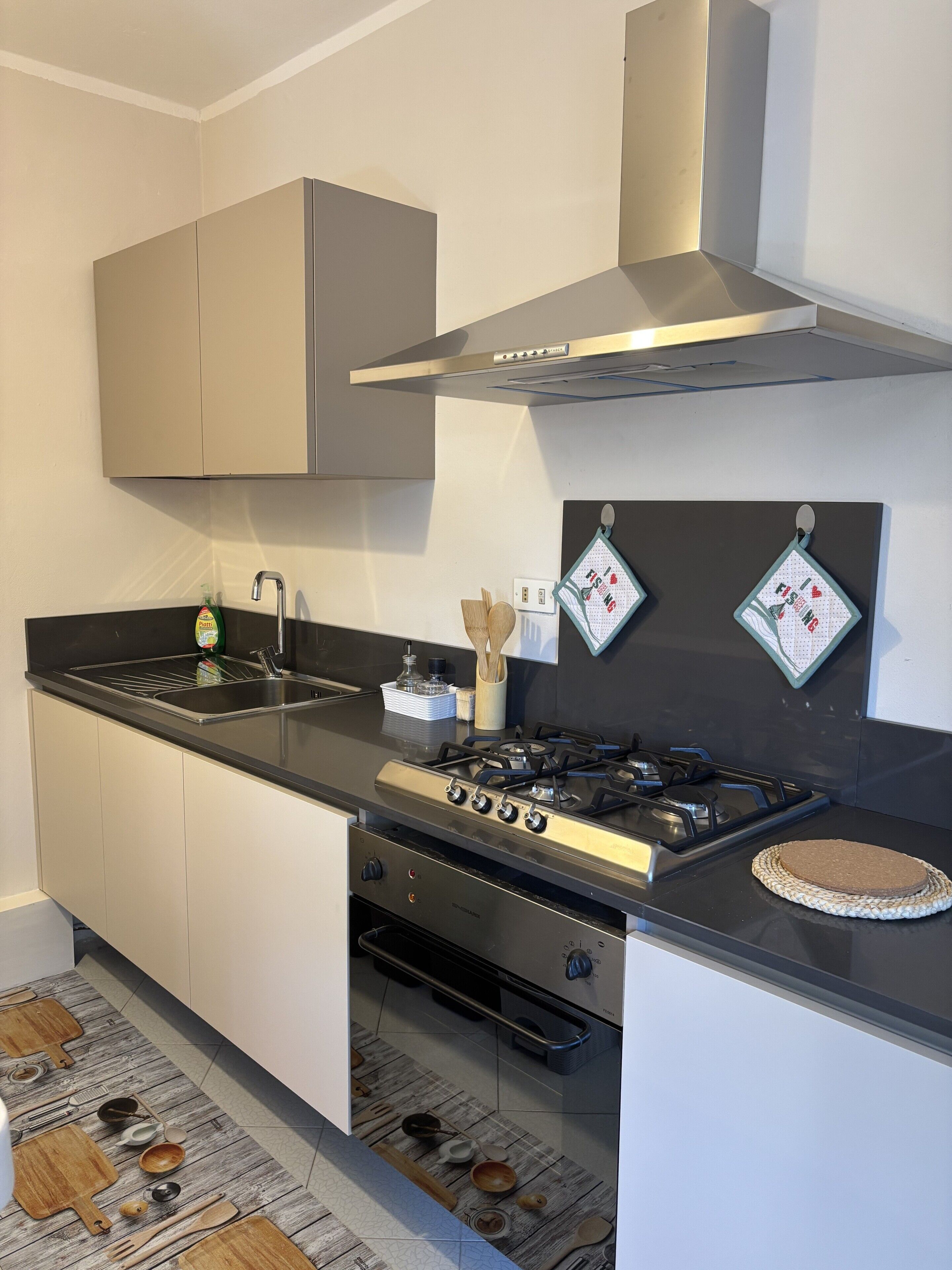 Eine moderne Küche mit Gaskochfeld, Spüle aus Edelstahl und Schneidebrettern aus Holz.