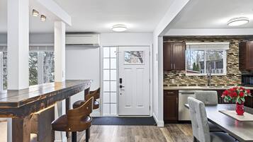 Een moderne keuken met een betegelde achterwand, houten keukenkastjes en een eethoek met een bar.