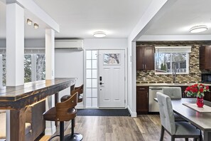 Une cuisine moderne avec un mur de crédence en pierre, des armoires en bois et un coin repas doté d’un bar.