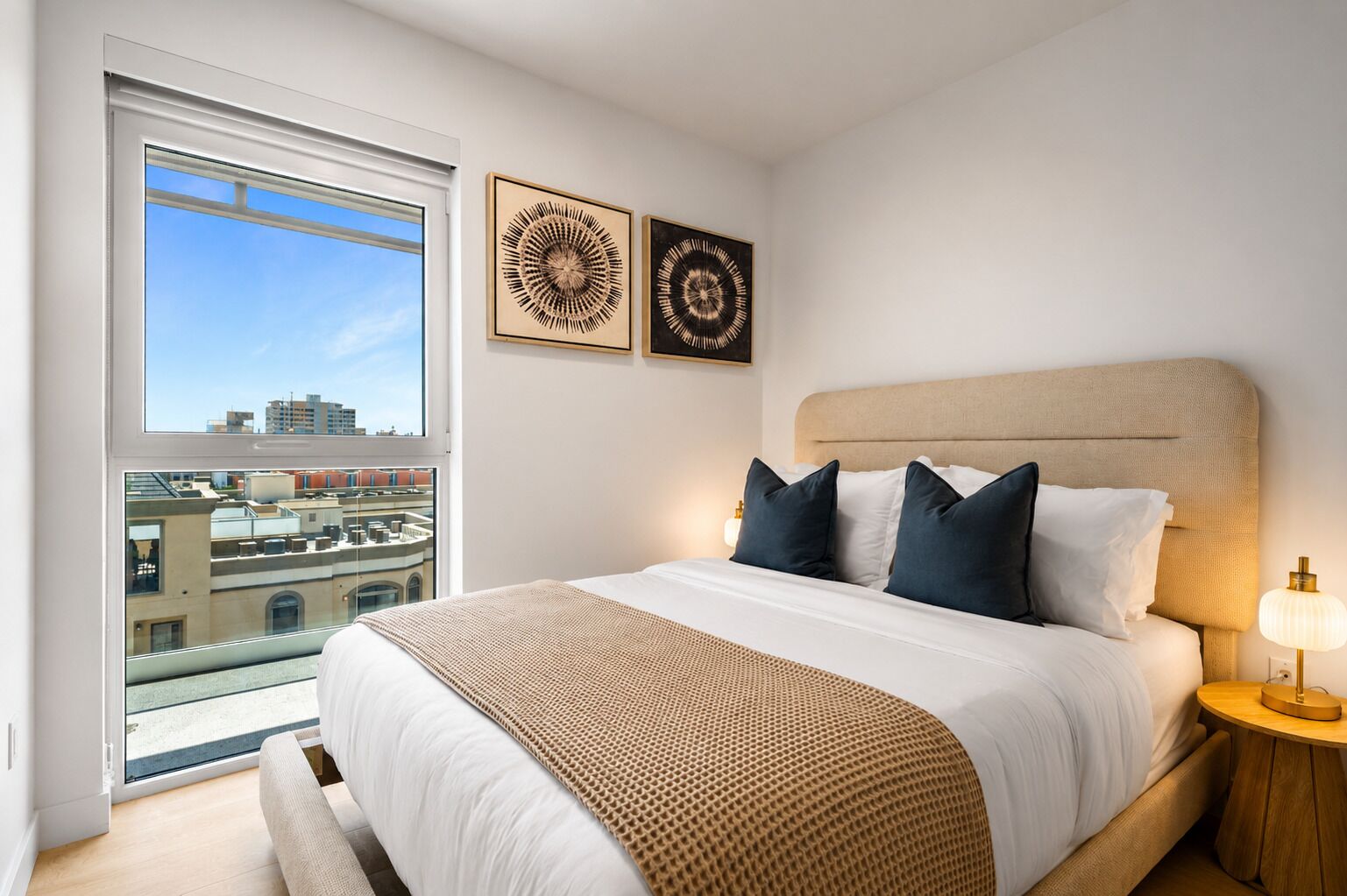 A hotel room with a large bed, a nightstand, a lamp, and two wall art pieces.