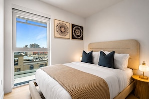 Una habitación de hotel con una cama grande, una mesita de noche, una lámpara y dos cuadros en la pared.