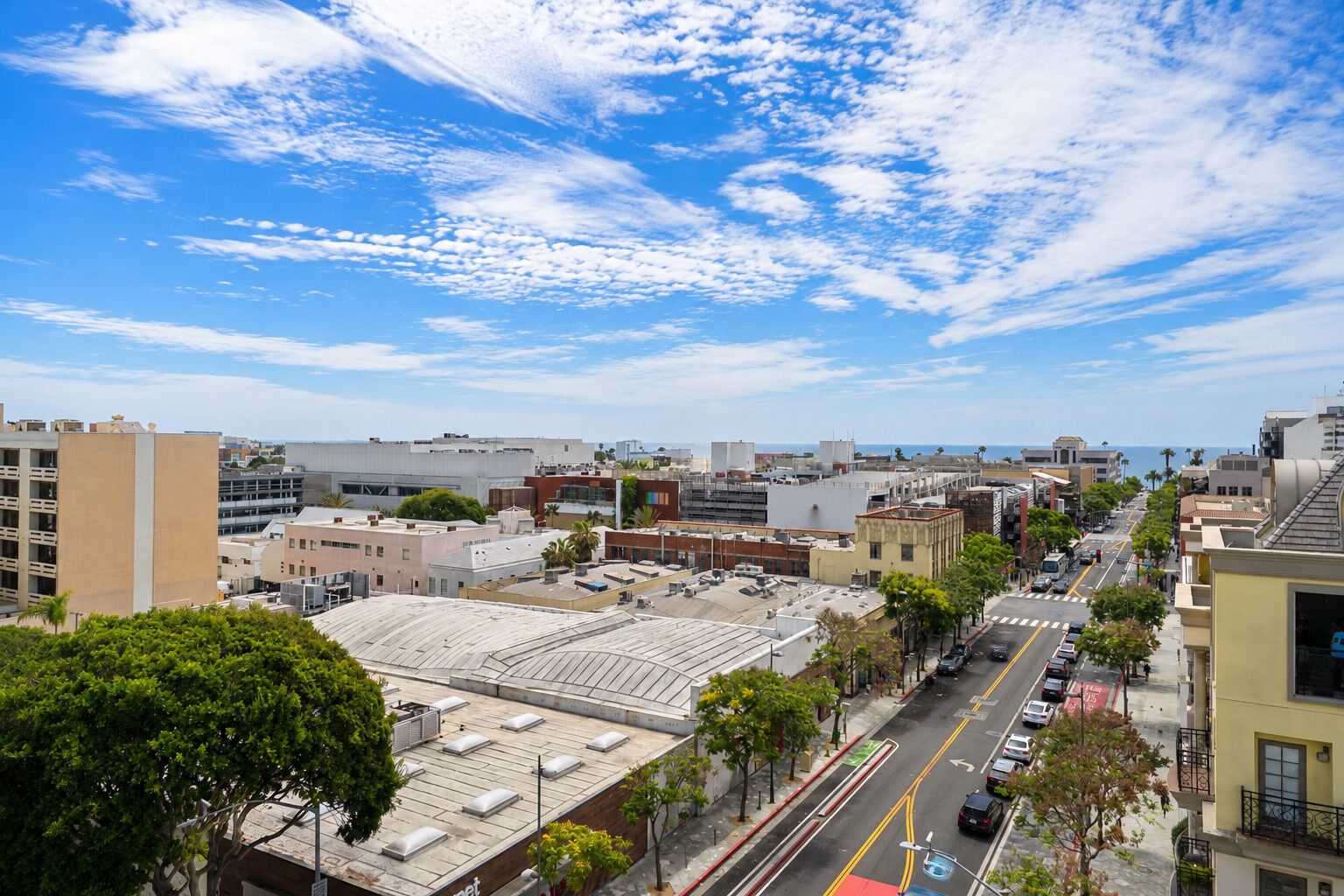A cityscape with a clear sky, buildings, and a street with vehicles.