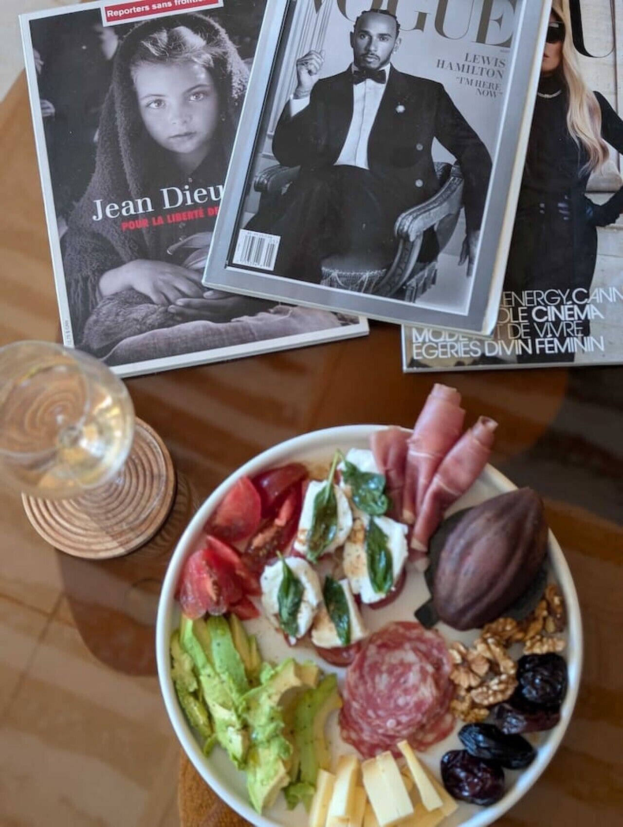 Ein Tisch mit einer Zeitschrift, einem Weinglas und einem Teller Essen.